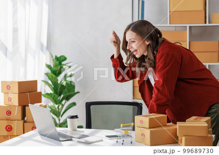 Concept of parcel delivery and selling online,Female seller or retailer happy while Using laptop check sales of day on online store to be packed into the parcel and ready to deliver to the customer Concept of parcel delivery and selling online,Female seller or retailer happy while Using laptop check sales of day on online store to be packed into the parcel and ready to deliver to the customer 99689730