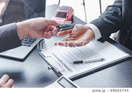 Concept of Car insurance or rental, salesman is making deal with buyer and giving key to him after sign sell contract or rental agreement. 99689744