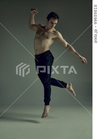 Full-length image of handsome young man with muscular athletic body posing shirtless in black pants over green studio background. Concept of men's health, beauty, sport 99689818