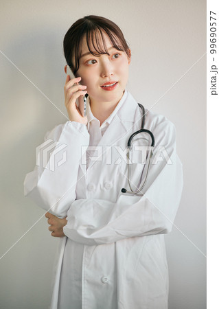 スマートフォンで電話をする女性医師 スマートフォンで電話をする女性医師 99690577