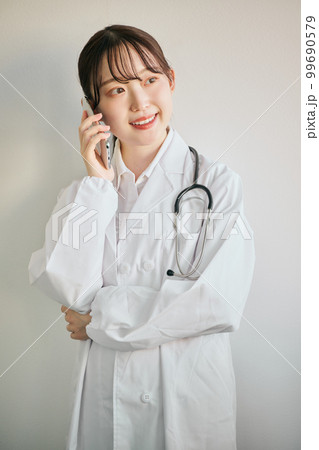 スマートフォンで電話をする女性医師 スマートフォンで電話をする女性医師 99690579
