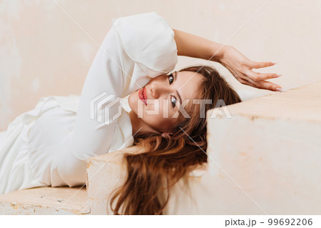 A barefoot beautiful young woman in a white romantic dress lies on the steps. 99692206
