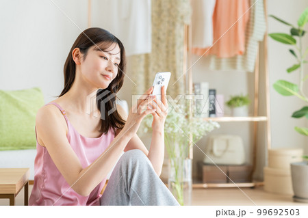 リビングでスマホを見る若い女性 リビングでスマホを見る若い女性 99692503