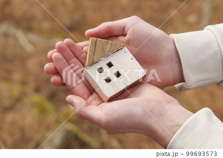 Wooden house model in the hands on a eco natural background of autumn fallen leaves. Eco housing concept Wooden house model in the hands on a eco natural background of autumn fallen leaves. Eco housing concept 99693573