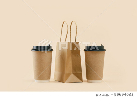 Takeaway two paper coffee cups with lunch bag on beige. Snack delivery service. Coffee to go. Grab and go or carry out beverage. Disposable mockup packaging. pair. Minimal 99694033