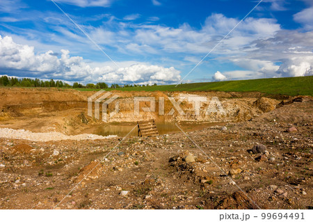 A dug pit in the middle of a beautiful landscape 99694491