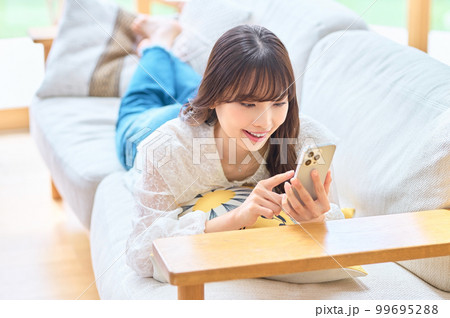 リビングでスマホをする若い女性 リビングでスマホをする若い女性 99695288