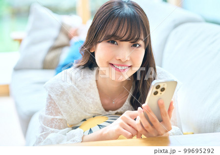 リビングでスマホをする若い女性 リビングでスマホをする若い女性 99695292