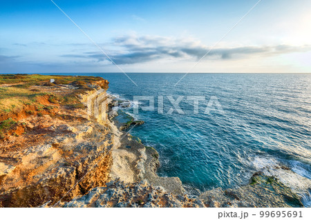 Stunning seascape with cliffs rocky arch and stacks (faraglioni) at Torre Sant Andrea Stunning seascape with cliffs rocky arch and stacks (faraglioni) at Torre Sant Andrea 99695691