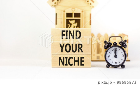 Find your niche symbol. Concept words Find your niche on wooden blocks. Black alarm clock. Beautiful white table white background. Business and find your niche concept. Copy space. 99695873