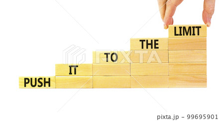 Push it to the limit symbol. Concept words Push it to the limit on wooden blocks. Beautiful white table white background. Businessman hand. Business push it to the limit concept. Copy space. 99695901