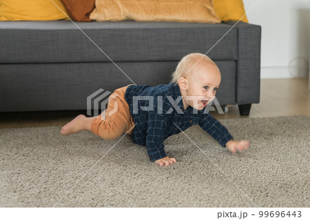 Nursery baby boy crawling on floor indoors at home - Baby curiosity and child development stages 99696443