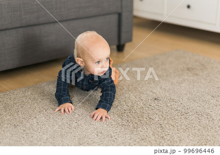 Nursery baby boy crawling on floor indoors at home copy space and empty space for text - Baby curiosity and child development stages 99696446