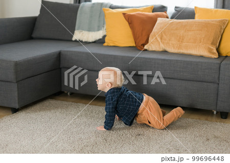Nursery baby boy crawling on floor indoors at home copy space and empty space for text - Baby curiosity and child development stages 99696448