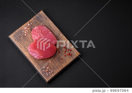 Two fresh slices of raw tuna fillet with spices and herbs Two fresh slices of raw tuna fillet with spices and herbs 99697064