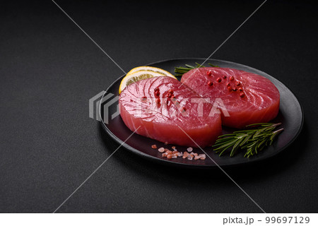Two fresh slices of raw tuna fillet with spices and herbs 99697129