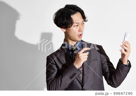 スマホでビデオ通話をしているスーツ姿の若い男性 スマホでビデオ通話をしているスーツ姿の若い男性 99697290