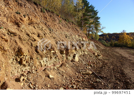 Part of the slope dug by an excavator with exposure of limestone rocks and clays of the Carboniferous period, lying under a layer of Quaternary deposits Part of the slope dug by an excavator with exposure of limestone rocks and clays of the Carboniferous period, lying under a layer of Quaternary deposits 99697451