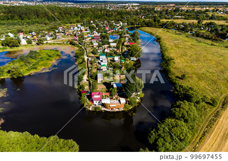 An aerial view of a dense suburban development on the shore of a winding reservoir 99697455