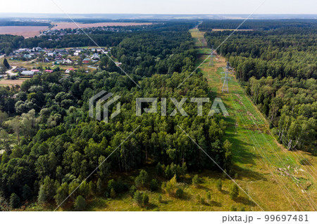 View of a high-voltage power line running through forests and countryside View of a high-voltage power line running through forests and countryside 99697481