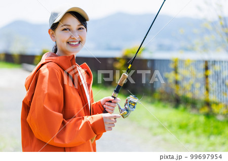 趣味の釣りを楽しむ笑顔の若い女性 99697954