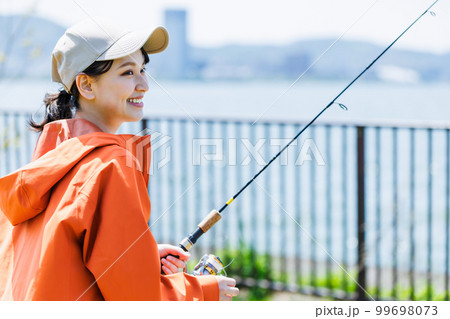 趣味の釣りを楽しむ笑顔の若い女性 99698073