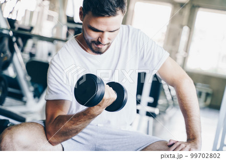 Wellness men lifting dumbbell weight hand in gym Wellness men lifting dumbbell weight hand in gym 99702802