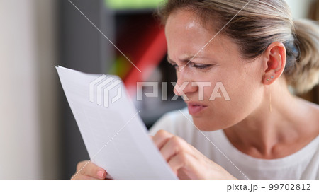 Focused female trying read text, squinting to see more clearly 99702812