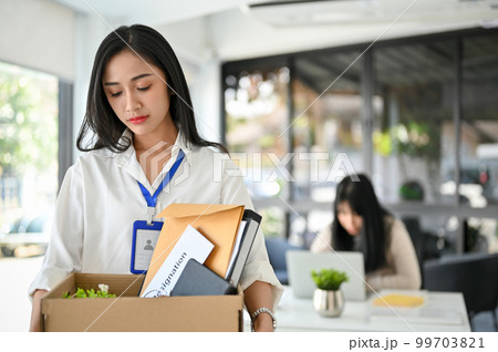 Sad and upset Asian female office worker walking out the company, being fired from her boss. 99703821