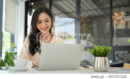 Attractive Asian businesswoman using laptop, working in her modern office. Attractive Asian businesswoman using laptop, working in her modern office. 99705168