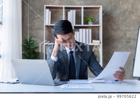 Stressed young asian businessman,Documents related to finance, tax ,push down calculator to calculate tax income and expenses, bills, office.Financial, finance concept 99705622