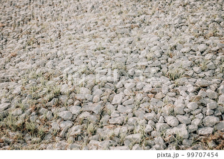 Granite stones behind a metal grate for strengthening the slope. Stones behind the wire. grey texture. construction. 99707454