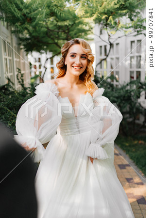 the bride by the hand with the groom walks through the garden. the bride by the hand with the groom walks through the garden. 99707841