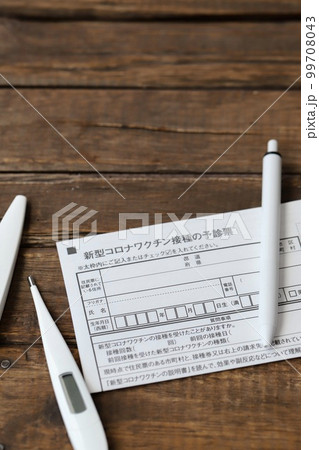 新型コロナワクチンの予診票と体温計とボールペン 99708043