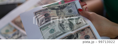 Counterfeiter cuts dollar bills with scissors closeup Counterfeiter cuts dollar bills with scissors closeup 99713022