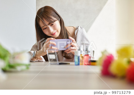 スマートフォンで化粧品を撮影する女性 スマートフォンで化粧品を撮影する女性 99713279