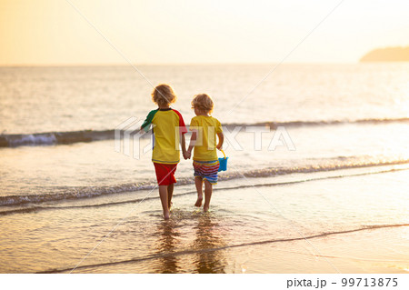 Child playing on ocean beach. Kid at sunset sea. Child playing on ocean beach. Kid at sunset sea. 99713875