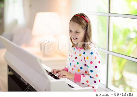 Child playing piano. Kids play music. 99713882