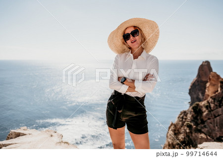 Woman sea hat. Business woman in yellow hat freelancer working over blue sea beach. Girl relieves stress from work. Freelance, digital nomad, travel and holidays concept 99714644