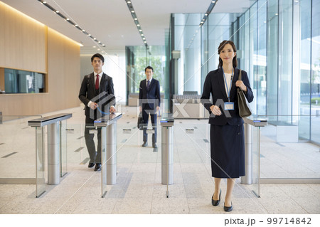 セキュリティゲートを通ってオフィスビルに入る男女のビジネスパーソン 99714842
