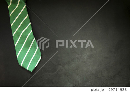 stylish tied green striped tie on dark concrete background top view, copy space, men,business,meeting,party concept 99714928