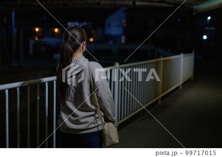 夜道を歩く女性の後ろ姿 99717015