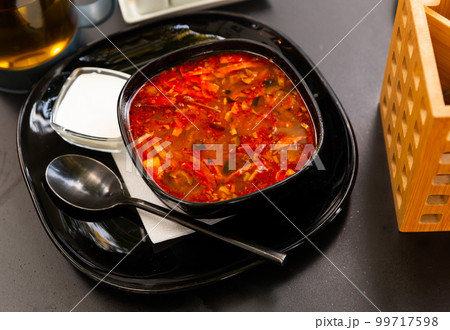 Delicious meat soup solyanka on broth served with sour cream and herbs closeup 99717598