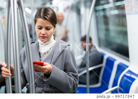 Woman with smartphone in subway car Woman with smartphone in subway car 99717847