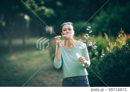 attractive young woman playing with soap bubbles in summer Park attractive young woman playing with soap bubbles in summer Park 99718872