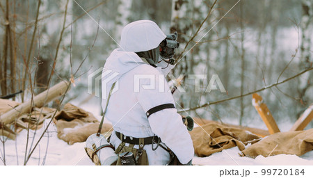 Multiple shots. Man Dressed As German Wehrmacht Infantry Soldiers In World War II Hidden Sitting With Weapon In An Ambush and looking at old army binoculars In Winter Day 99720184
