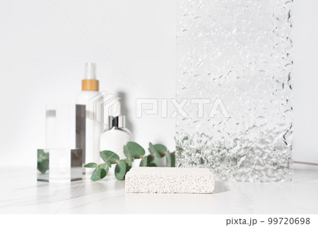 Cosmetics and beauty product presentation scene made with porous stone podium on white bathroom shelf. 99720698