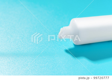 White tube with creamy paste on a blue background. White tube with creamy paste on a blue background. 99720777