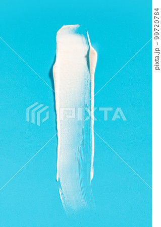 White cream smear on a blue background. Vertical macro photography. 99720784