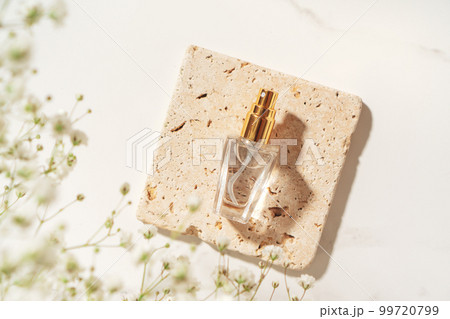 Summer fragrance concept made with perfume bottle on travertine plate in sunlight. Summer fragrance concept made with perfume bottle on travertine plate in sunlight. 99720799